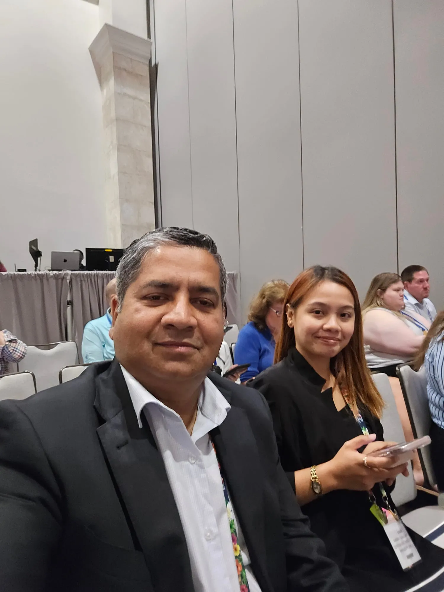 Sohan David and Shaira Valdez of TBS Global seated in the audience at a symposium session